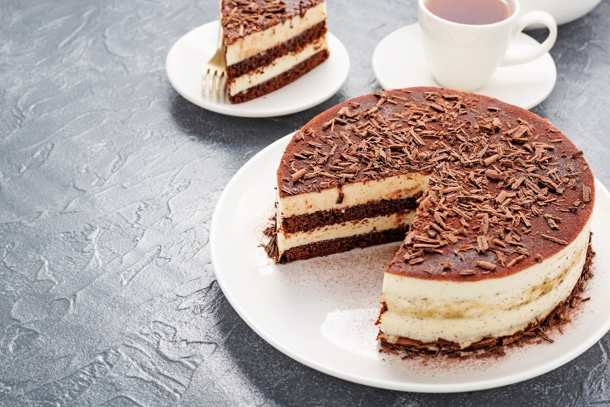 An eggnog tiramisu cake with a slice taken out. Next to it is a cup of coffee.