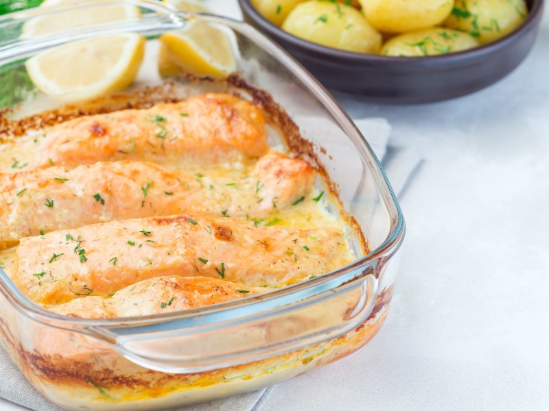 Baking dish with salmon gratin on a light background