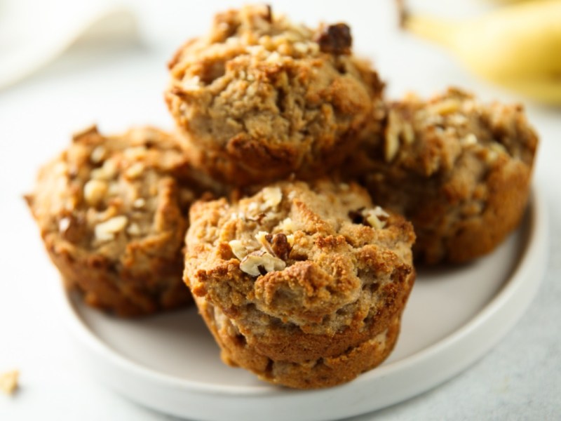 Four breakfast muffins with oatmeal and nuts on a plate.