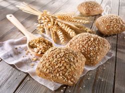 Oatmeal rolls lined up, napkin and ears of wheat in the background as decoration.