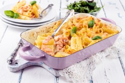 Baking dish filled with a salmon pasta bake on a light background