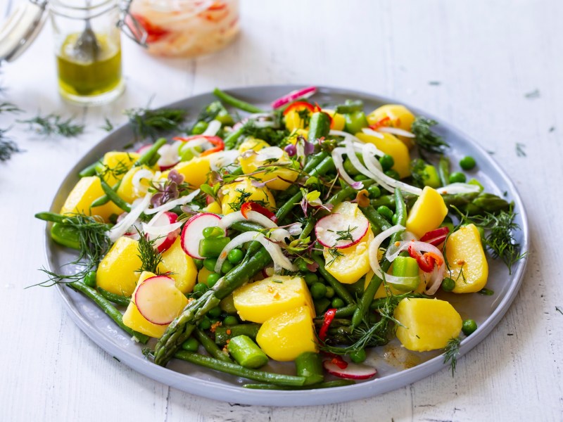Plate with asparagus and potato salad on a light table
