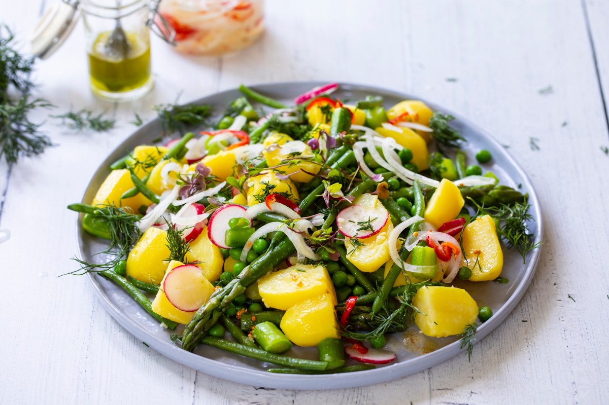 Plate with asparagus and potato salad on a light table