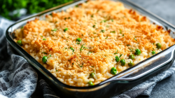 Chicken Alfredo Rice Casserole with peas and breadcrumbs in a square glass baking dish.
