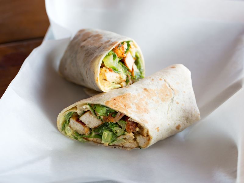 Sliced Chicken Caesar Wraps lying on parchment paper.