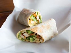 Sliced Chicken Caesar Wraps lying on parchment paper.
