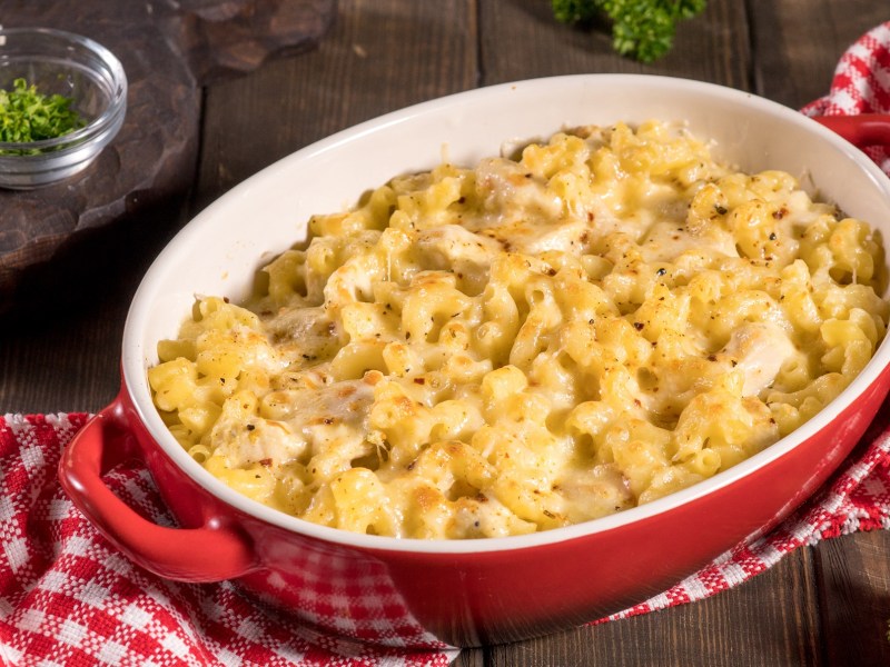 A casserole dish with Chicken Noodle Casserole on a white and red checkered tablecloth