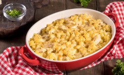 A casserole dish with Chicken Noodle Casserole on a white and red checkered tablecloth