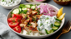 A Chicken-Tzatziki bowl with tender meat and crunchy vegetables. Next to it is a fork.