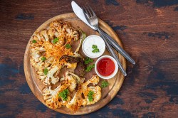 Grilled cauliflower steaks with dips on a board