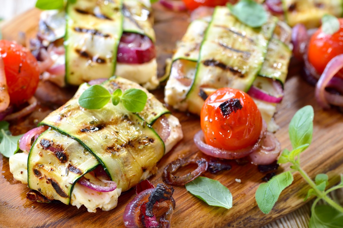 Wooden board with grilled feta and zucchini packets