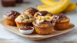 Nutella-banana muffins served on a plate. Next to it is a small bowl of Nutella.