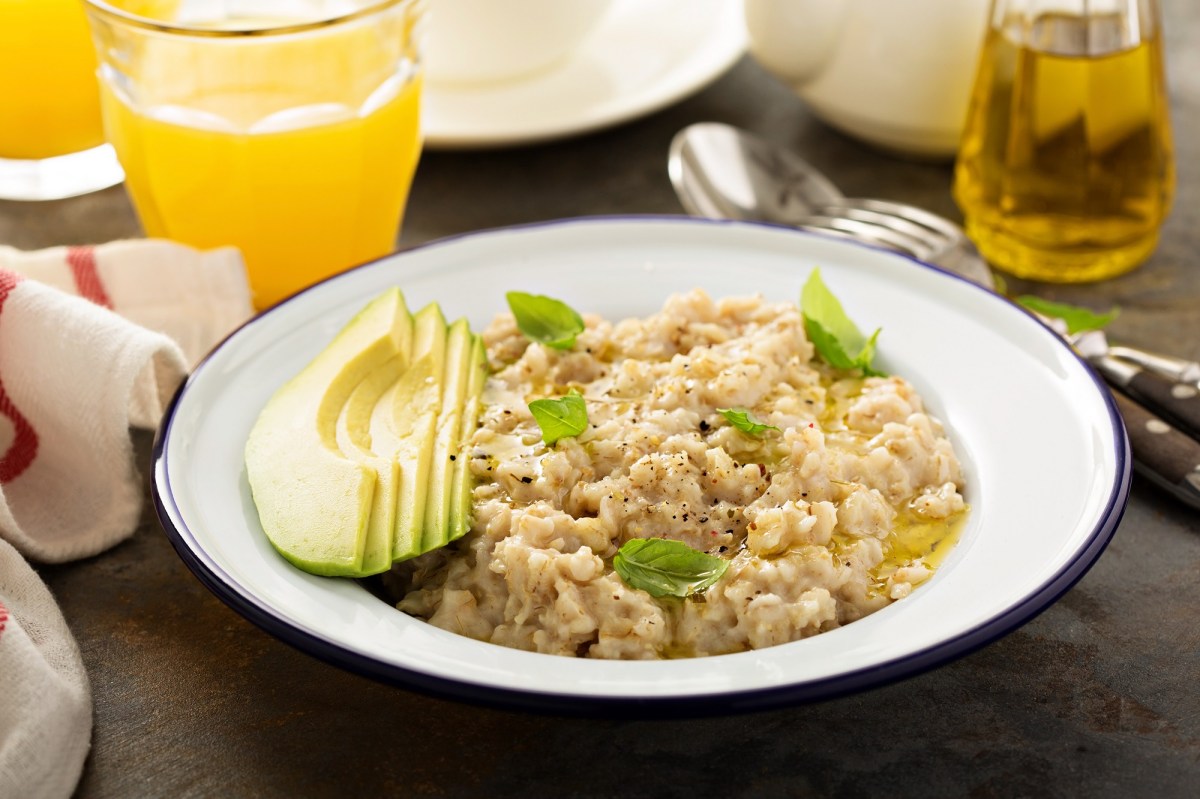 Oatmeal with avocado and olive oil on a plate, accompanied by drinks.
