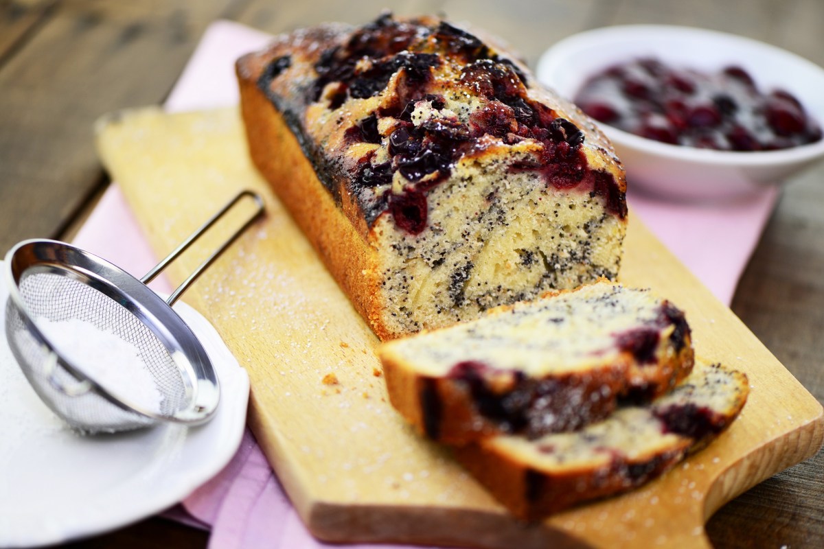 Sliced poppy seed cake with cherries on a wooden board