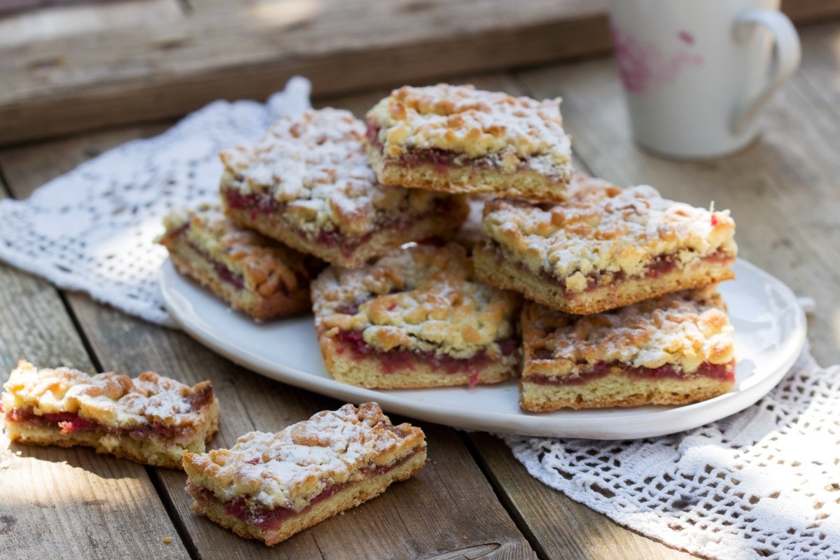A stack of red berry bars with powdered sugar on a plate.