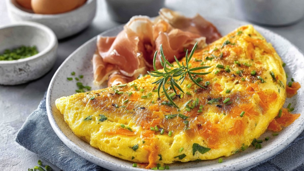 A carrot omelette with ham on a plate.