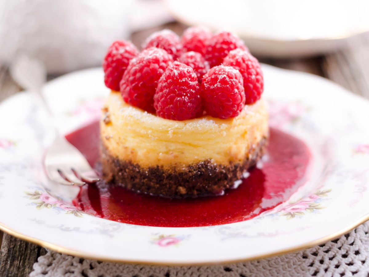 Cheesecake muffins with raspberries on a raspberry mirror.