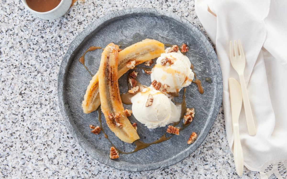 Grilled banana with walnuts and vanilla ice cream on a plate. Top view.