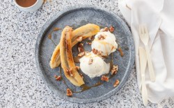 Grilled banana with walnuts and vanilla ice cream on a plate. Top view.