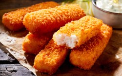 Some homemade fish sticks. A bowl of dip in the background.