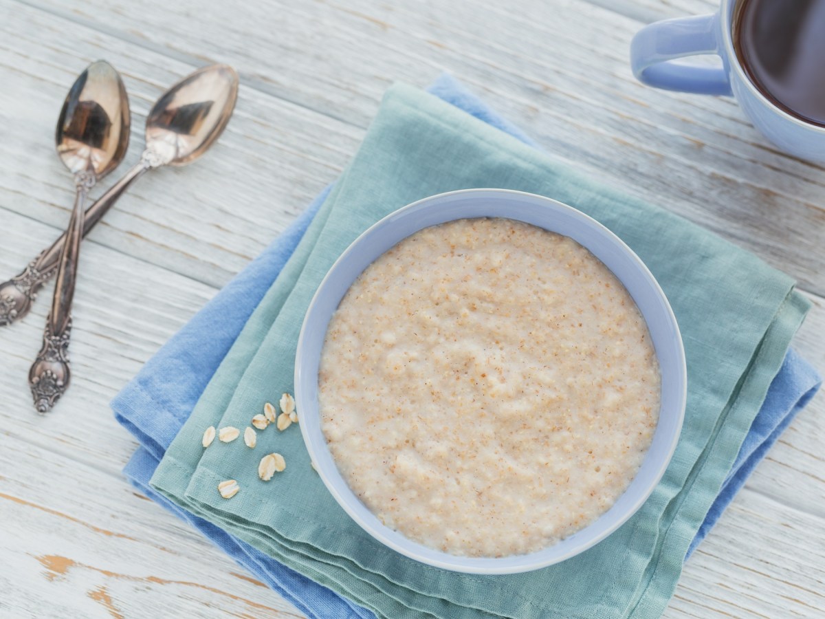 Scottish porridge in a light blue bowl, two spoons lying next to it.