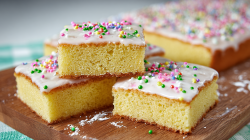Several pieces of Sprite cake on a wooden board, with the rest of the cake in the background.