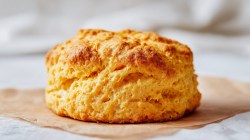 Golden cheddar honey biscuit on a napkin in full frontal view and white lighting.