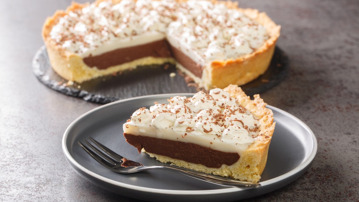 A piece of haupia pie on a plate. The rest of the pie is in the background.