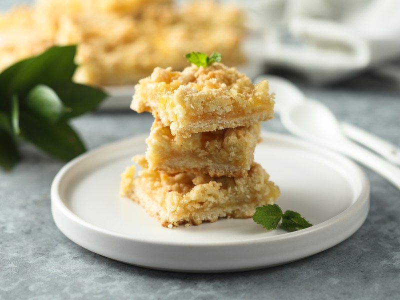 Three lemon crumble bars on a plate.