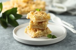 Three lemon crumble bars on a plate.