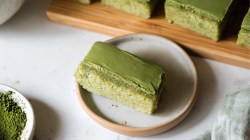 A matcha mochi brownie on a plate. More brownies can be seen in the background.