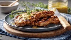 Two mustard-marinated schnitzels on a plate.