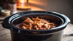 An aerial shot of slow cooker bbq pulled chicken in a small bowl in light whiting.sc-slow-cooker-bbq-pulled-chicken.