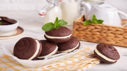 Several whoopie pies on a plate, surrounded by some tableware.