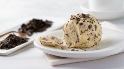 Plated truffle butter with truffle shavings next to it in frontal view and bright lighting.